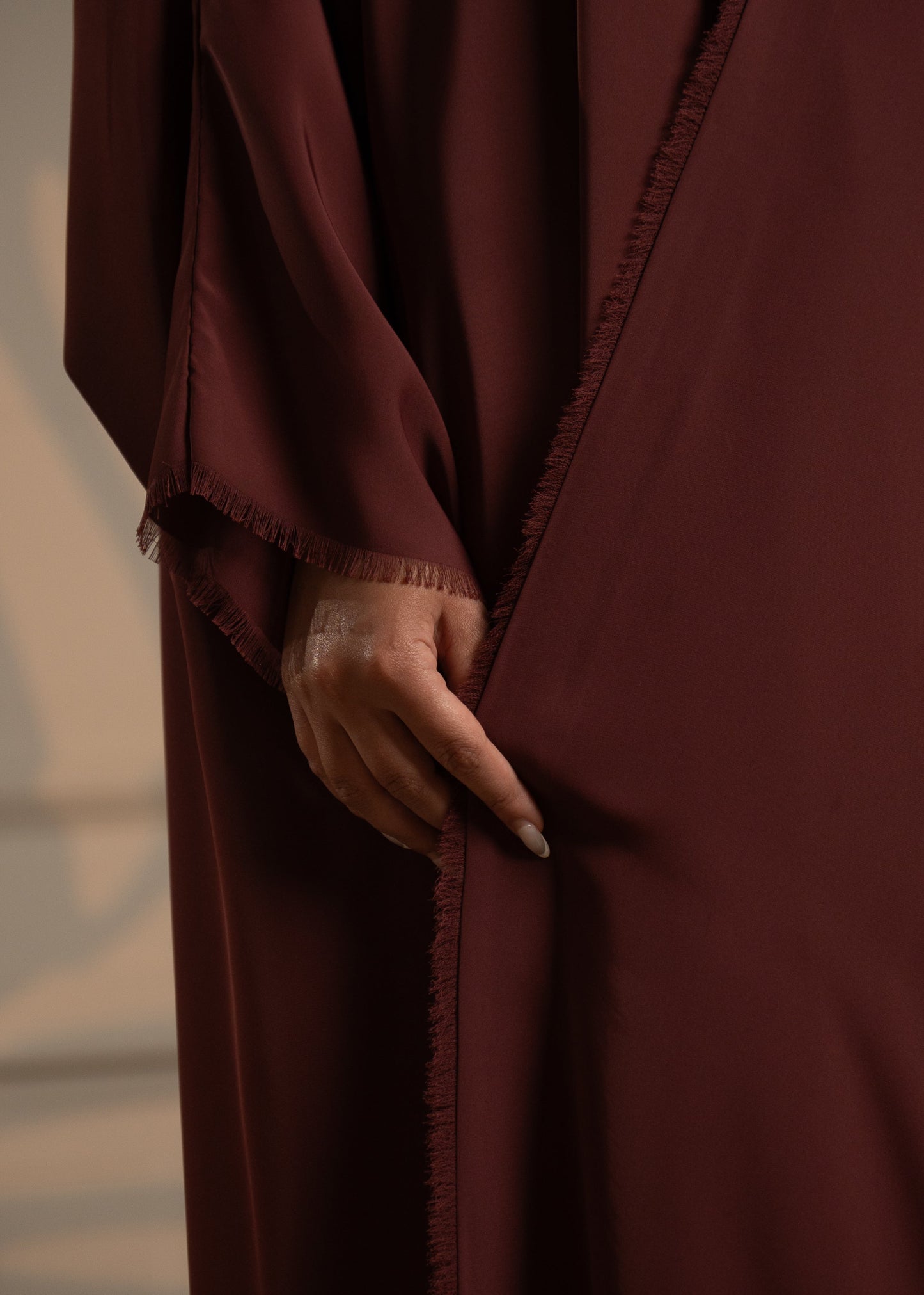 Brown garment with a hand touching the fabric against a neutral background