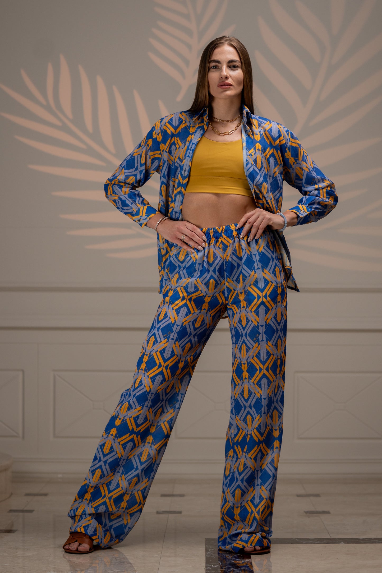 A relaxed-fit linen Sunline Shirt in yellow and blue with a classic button-front design, long sleeves, and a curved hem. The lightweight, breathable fabric has subtle texture, perfect for casual or beachwear. Styled untucked over white shorts for a laid-back summer look.